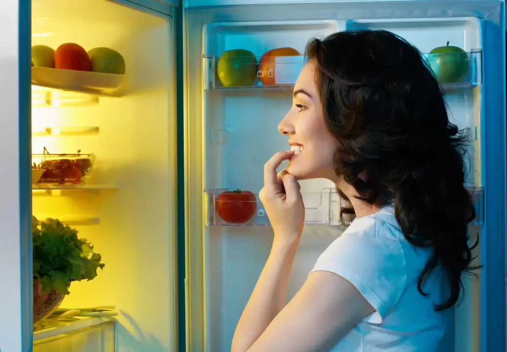 mergina žiūri į šaldytuvą greito svorio metimo metu